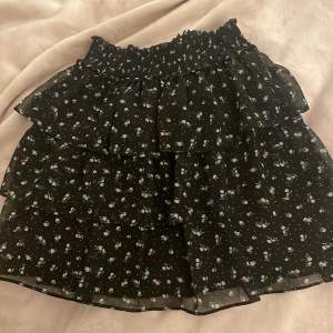 Somrig volangkjol från H&M. Svart kjol med små blommor på. Nästan aldrig använd och ser ny ut. Storlek xs.