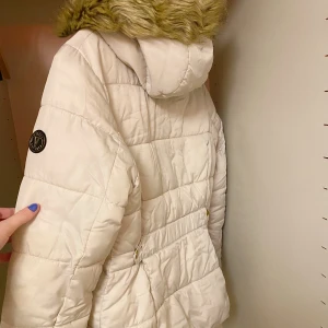 Vinterjacka - En beige vinterjacka med rosa innerfoder. Sparsamt använd :)