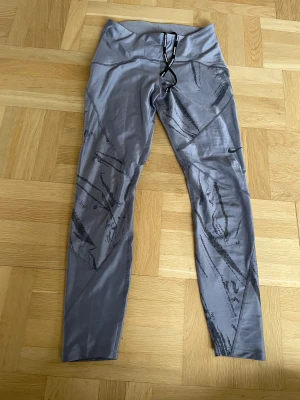 Löpartights från Nike - Ett par löpartights från Nike som är reflex. De är högmidjade, har dragsko och två stora fickor. Innerbens sömmen är 65cm. Använda 5 gånger, nytt skick