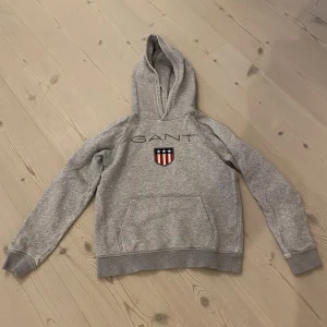 GANT Hoddie Strl. 146/152 - En GANT-Hoddie relativt väl använd säljs nu på grund av för liten. Skick: 7/10 Kan fraktas men då står köparen för frakten:)
