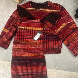 Nelly set kjol o topp - Ett Nelly set med en mini skirt och en långärmad topp med en slits längst ner, kjolen är aldrig använd och prislappen är kvar.