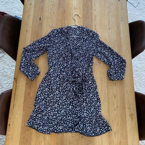 Klänning - Mörkblå omlottklänning med vita blommor från Only. Storlek 36/S. Skulle nog säga den är relativt true to size. Har tyvärr aldrig kommit till användning, så som ny! 