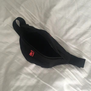 Poetic Collective Belt Bag Black / Red - Svart magväska med rött embroderi från Poetic Collective. Runt 30 cm i längd och 15 cm i bredd. Pris kan diskuteras, kan fraktas.