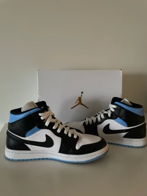 Air Jordan 1 MID - Ett par Air Jordan white/black University blue. Storlek 41.  Knappt använda i väldigt bra skick och orginalkartong medföljer.