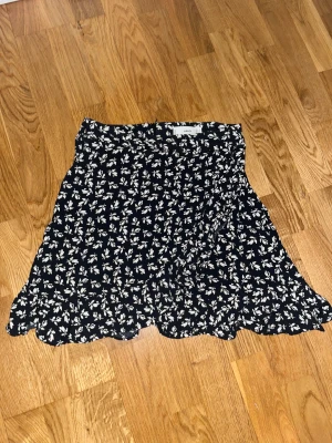 Kjol - Fin kjol med slits och blommor. Jag säljer den för den har blivit för liten för mig. Kjolen är i bra skick. 