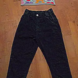 Blommig magtröje linne & ett par svart-gråa utslängda jeans med resår i midjan.