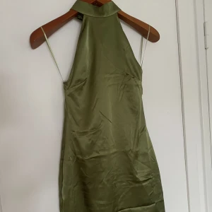 Satinklänning - - Grön midiklänninig i satinimitation från Bik Bok  - Hög krage med knytning bak samt låg rygg med dragkedja  - NYSKICK : Aldrig använd med lapp kvar  - Färgen är mest lik sista bilden med dagsljus utan skugga  - Kan tyvärr inte ta fitpica pga för liten