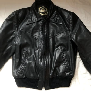 Svart läderjacka  - Vintage Svart Läderjacka, kan tyvärr inte säga om det är äkta läder eller inte för det står inget på lapparna..! I använt men fint skick! Den saknar knapparna på ärmen, Har ersatt det med nålar och har funkat bra!Står ingen storlek men uppskattar till S-M
