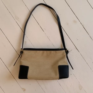 Axelremsväska  - Axelremsväska i färgen beige med svarta remmar. Oanvänd 😊 