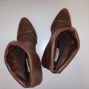 Steve Madden - bruna stövletter i skinn - leather ankle boots - Bruna stövletter i skinn från Steve Madden. Tror att modellen heter Aplegate. Använda bara någon enstaka gång och i fint skick (ett litet märke nere på ena klacken där lädret skrapats upp). Svårt att fånga hur snygga de är på bild. Väldigt fin kvalitet på lädret. Hittar inte storleken någonstans men antar att det är 39-40. Mätte sulan utvändigt om den är ca 25 cm om man räknar bort toppen av spetsen. 