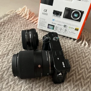 Sony alpha 6000 - Säljer min kompakta systemkamera som fungerar toppen.  På kameran just nu sitter ett sigma 30mm 1.1.4 objektiv som är alldeles nytt och endast använd en gång.    Sony Power Zoom-objektiv medföljer också. Laddare, USB/ HDMI kabel, kartong,kvitto och Axel band medföljer. Kameran är ca 2år gammal och använd bara ett fåtal gånger. Så fungerar felfritt och är i nytt skick:) Hör av dig vid frågor eller funderingar!  (Går att läsa mer om kameran och alla bra funktioner, om du söker, annars hör av dig:)