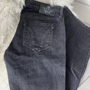Lågmidjade utsvängda jeans - Mörkgrå lågmidjade utsvägnda jeans från Gina. Står ingen storlek men skulle säga att de passar 36-38. Köpt secondhand.