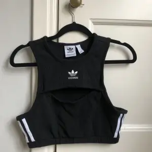 Adidas croptop med märket fram på bröstet, cutout och tre tänder på sidorna. Helt ny aldrig använd. Frakt 60kr😽