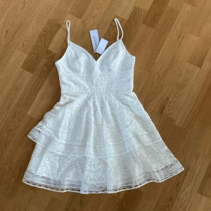 Vit klänning - En superfin vit spetsklänning, oanvänd. Passar utmärkt till studenten😊Sitter tajtare i midjan och får ett fint fall längs benen. 550 kr + frakt✨(ord pris 1026 kr)