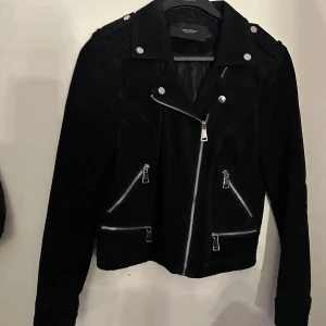 Svart mocka jacka  - Svart mocka jacka med silvriga detaljer. Storlek L men liten i storleken, sitter bra på mig som har storlek S. Knappt använd. Köpt på Vero Moda. Nypris 1000kr. Kan mötas upp i Skövde eller frakta. Köparen står för frakt. 