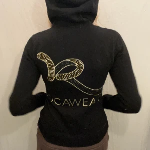 Rocawear Hoodie - Svart Hoodie med paljetter och guldigt tryck av Rocawear. Fint skick. 