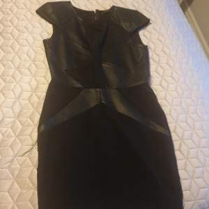 En svart klänning från Guess som har använts 2 gånger. Mixed material i läder imitation och stretch.Nypris 1400. Jag säljer den för att jag gått upp i vikt och har inte kunnat använda den på flera år.