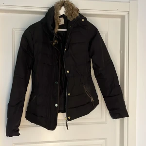 Vera moda jacka - Svart jacka, fickorna har dragkedjor, fuskpäls på insidan av kragen, resor i midjan. I använt skick utan defekter. 