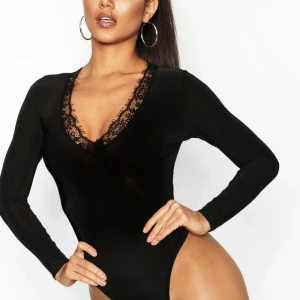 Body med spets  - En svart Body med v-ringning och spetsdetalj från boohoo. Stretchig och jätte skön material. Oanvänd med prislappar på. Ordpris.217kr