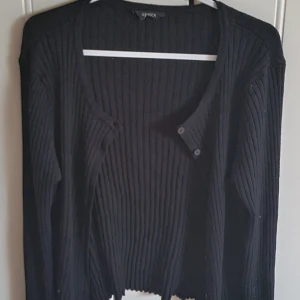 Svart kofta stl. M - Svart, ribbstickad kofta med knappar från Lindex. Storlek M/medium. Endast använd ett par enstaka gånger.