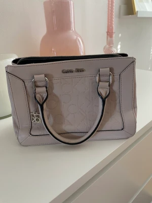 Calvin Klein-väska - Säljer min älskade väska från Calvin Klein. Köptes för cirka 2 år sedan och får inte användning av den längre. Finns ett långt band till. Lite avskavd i ena kanten (se bild) därav priset. Nypris var 1200 kr ☺️