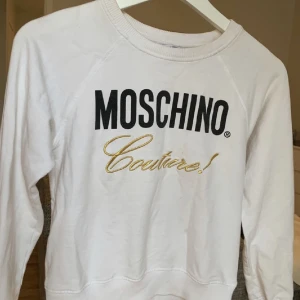 Mochino tröja - Vit äkta Moschino tröja köpt i London. Knappt använd, storlek 140 men passar mig som har XS. Skriv om ni vill ha bild på hur den sitter på. 