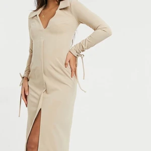 Beige skjortklänning  - Skjortklänning, djup urringning och knytning vid ärmarna. 