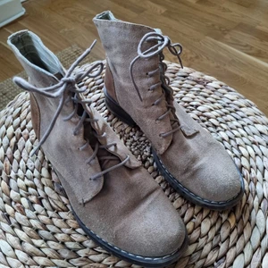 Beiga mockakängor - Beiga mockakängor med skinndetalj på hälen. Använda men har vårdat skinnet så de är i fint skick och har mycket mer att ge! Från Scorett, märke D for Dasia. Storlek 38, upplever dem som något stora i storlek - jag har normalt 39. Innermått 25 cm.