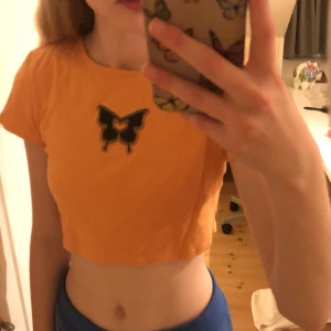 Orange topp - En jättefin orange topp med en fjäril från hm, bra skick använd ca 5 gånger