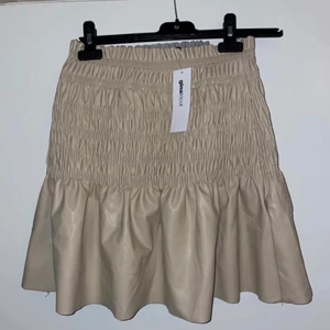 Ny kjol - Oanvänd beige kjol i fake skinn. Storlek S, säljs för 100kr