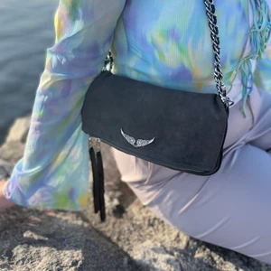 Zadig och Voltaire väska - rock mocka - Grå zadig väska modell Rock. Materialet är mocka- därav den uppleva ”fläckig” på bild men det finns inga permanenta fläckar på den! Båda band finns! Säljer för halva priset:)) Buda gärna över 1000