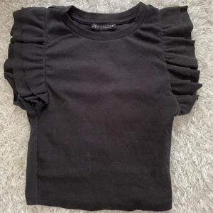 Volangtopp Zara - Svart topp från zara med volanger, köpt för ett tag sedan på zaras hemsida för 119 kr.  Endast använd 1 gång, tvättar innan jag skickar!💗 Om man ej vill ha spårbart kan jag skicka med frimärken för 26 kr, annars 51 kr. Kontakta mig vid intresse!💘