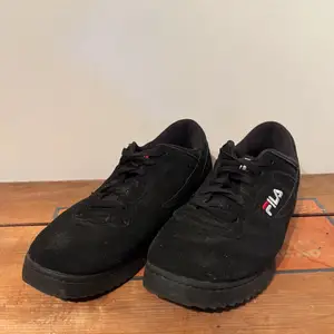 Ett par svarta Fila skor i mocka
