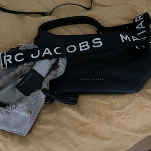Marc Jacobs  - Mycket fin Marc Jacobs väska i skinn. Inuti finns ”påse som går att dra ihop. Funkar att styla genom att dra ihop den till lite ”bo-ho”- stil men går även att styla mer strikt. Kommer även med axelrem. En tunn orginal i skinn och en i svart canvas. 
