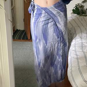 Lila och blå batikmönstrad Långkjol som man knyter runt sig.