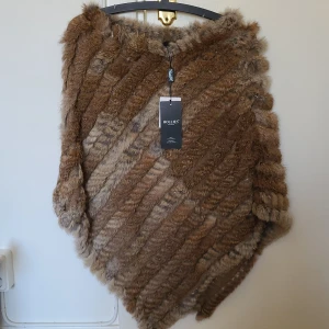 Hollies poncho -  Päls poncho från Hollies. Äkta kanin päls. Aldrig använd,köpt för 1399kr.  Storlek onesize Kan skickas inom Sverige