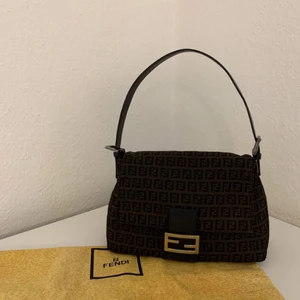 Fendi Mamma Baguette vintage  - Fendi Mamma Baguette vintage  Mått W30,H19,D11. Serienummer finns inne i väskan och medföljer dustbag. Axelrem börja blir blekt färg men allt annat är fint. Finns ute på Vestiaire,Tradera och Tise. Kan skickas flera bilder vid intresserad. 
