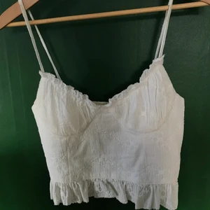 Vit croppad topp - 💕Ett urringat croppat linne i blommigt mönster som jag köpte helt nytt här på plick! Säljer då jag inte använder det 💕