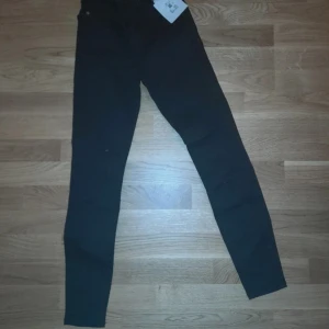 Nya! Svarta Peachy high waist jeans XS - Svarta jeans från Peachy i storlek XS med ankellängd. Modellen har curved high waist och tighta ben, vilket ger en snygg och smickrande siluett. Klassisk femficksdesign och tillverkade i stretchigt jeanstyg för extra komfort.