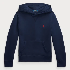 Marinblå hoodie från Polo Ralph Lauren - Snygg marinblå hoodie från Polo Ralph Lauren med klassisk röd logobrodyr på bröstet. Tröjan har huva, känguruficka och långa ärmar. Tillverkad i mjuk bomull som är skön mot huden. Perfekt för chill dagar och enkel att matcha med jeans eller joggers. 14/XS.