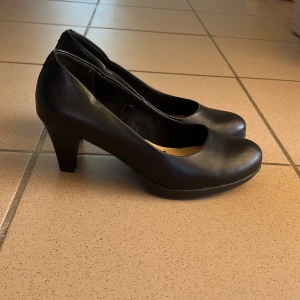 Svarta pumps från Gyllene Gripen - Stilrena svarta pumps från Gulden Gripen med rund tå och klassisk klack. Perfekta för dig som gillar en clean och elegant look.