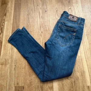 Blå jeans från Dondup med slitningar - Snygga blå jeans från Dondup med klassisk femficksdesign och coola slitningar på knäna. Jeansen har raka ben, kontrastsömmar och en läderpatch med logga bak. Materialet är mjukt jeans och passformen är normal. Perfekt för dig som gillar en avslappnad stil- pris kan diskuteras😊