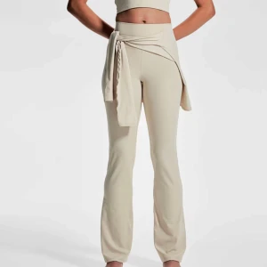 Yogapants - Snygga beige träningsbyxor från H&M Move i storlek M. Byxorna är högmidjade och har raka ben med lätt utsvängd passform. Tillverkade i ett mjukt och stretchigt syntetmaterial som andas, perfekta för träning eller chill.