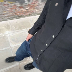 Morris skjorta - Svart skjorta från Morris med klassisk button-down krage och vita knappar. Liten Morris-logga broderad på bröstet. Skjortan är långärmad och har en stilren, normal passform. Perfekt för dig som gillar enkel och snygg stil.