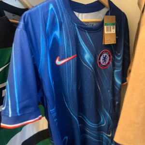 Chelsea Palmer #10 blå Nike fotbollströja - Chelsea FC matchtröja med Palmer och nummer 10 på ryggen. Snyggt blått mönster med ljusa och mörka toner, Nike-logga i rött och Chelsea-emblem på bröstet. Kortärmad och tillverkad i lätt, ventilerande material som passar perfekt på planen.