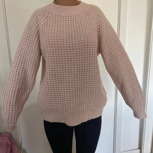 Ljusrosa stickad tröja från 157 - Mysig ljusrosa stickad tröja från 157 i storlek S. Tröjan har ett grovt, luftigt stickat mönster och ribbade muddar vid hals, ärmslut och nederkant. Passformen är loose och den har långa ärmar, perfekt för chilliga dagar.