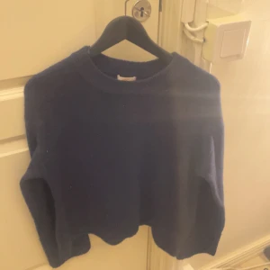 Mörkblå stickad croppad tröja - Säljer en mörkblå stickad tröja med croppad passform och rund hals. Tröjan har långa ärmar och är perfekt för dig som gillar en enkel men snygg look. Passar dig som vill ha något mjukt och bekvämt till hösten eller vintern.