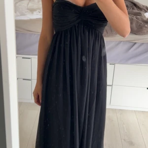 Svart balklänning - Svart axelbandslös långklänning från Trend i storlek XS. Klänningen har ett snyggt twistat bröstparti och faller mjukt med ett skirt yttertyg. Lite lång för mig som är 165. Små defekter längst ner men inget som syns på 