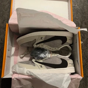 Nike Air Jordan x Louis Vuitton sneakers - Unika sneakers med Nike Air Jordan och Louis Vuitton branding. Skorna har en snygg kombination av grå mocka och vita skinnpaneler, svart swoosh och detaljer på hälen. Rund tå, platt sula och snörning. Kommer med extra skosnören och cool orange box.