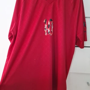 Röd Messi fotbollströja från Adidas limited edition  - Säljer en röd fotbollströja från Adidas med Messi-tryck och nummer 10 på bröstet. Tröjan är i funktionsmaterialet Climalite och har korta ärmar. Snyggt diskret rutmönster i tyget och svarta detaljer på ärmen.